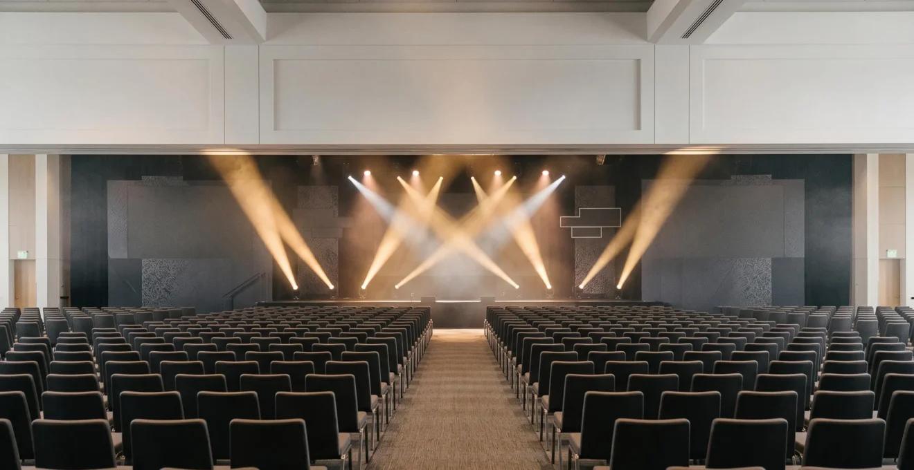 Vue large d'une salle d'événement professionnel illuminée symbolisant la convergence d'une campagne marketing multicanale