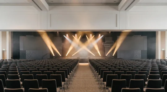 Vue large d'une salle d'événement professionnel illuminée symbolisant la convergence d'une campagne marketing multicanale