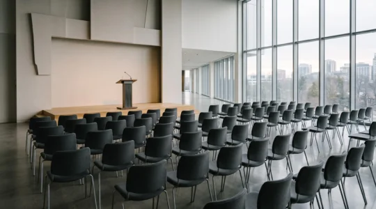 Salle de conférence de presse vide juste avant l'arrivée des journalistes, symbolisant la préparation stratégique de la visibilité médiatique d'un événement